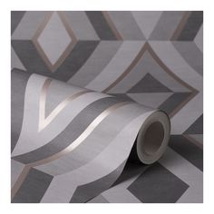 a roll of metallic foil on top of a gray wallpaper with geometric design in the background