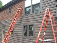 two ladders leaning against the side of a house with another ladder in front of it