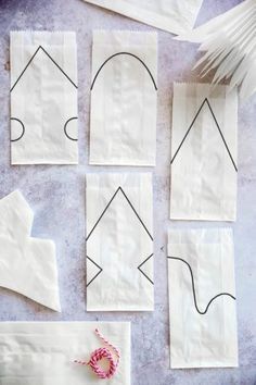 several pieces of white paper with black lines cut out on them and tied to strings