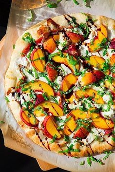 a pizza sitting on top of a cutting board covered in cheese and fruit toppings