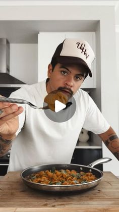 a man holding a spoon over a pan filled with food