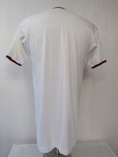 "Vintage 1950s Harvard college t shirt. Made of white cotton with Burgundy trim. Harvard with the Harvard crest. Has old goal runner label. Size large. Actual measurements are: 38\" around the chest 38\" around the waist 19\" shoulder to shoulder 32\" overall length In excellent unused condition, new old stock. it does have a faint dust line from storage near the crest, it will clean, but I wanted to leave original." Cotton Shirt With Contrast Collar, Short Sleeve, Cotton Shirt With Contrast Collar And Short Sleeves, White College T-shirt With Three Stripes, White T-shirt With Three Stripes, Vintage Tan Short Sleeve Tops, Vintage Style Tan Cotton Tops, White Collegiate T-shirt With Three Stripes, College Cotton T-shirt With Three Stripes, Fitted Retro Cotton T-shirt