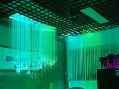 a room with green lights and curtains on the ceiling, in front of a mirror