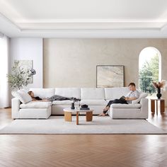 two people laying on couches in a living room with hardwood floors and white walls