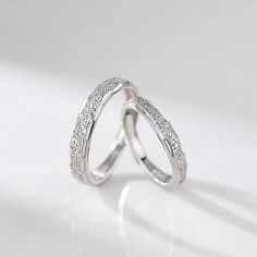 two white gold wedding rings with pave set diamonds on each side, one in the middle