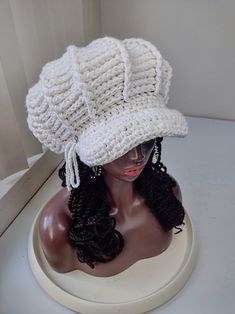 a mannequin head wearing a white crochet hat with black braids