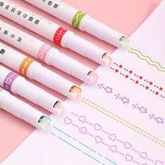 four pens sitting on top of a pink surface