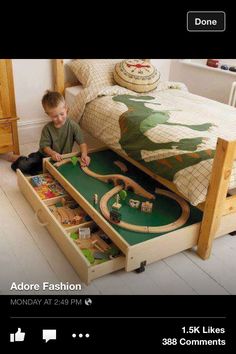 a young boy playing with his toy train set on the floor in front of a bed