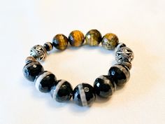 Large Tiger Eye and Black Agate Beaded Bracelet.  Sold as individual units.  7.5 inches  Size can be adjusted. Please allow two additional days for size adjustments.  Some images show multiple images for styling tips#blackfridaysale #blackfridaydeals #trecieshoppe #giftsforhim #giftsforher #giftideas #christmasgifts #armcandy #bracletstacks #bracelets #jewelry#bhm #womanownedbusiness #blackownedbusiness #treciesshoppe #trecies #armcandy #braceletstacks #mensstyle #sytleinspiration #Womensstyle # Black Bohemian Bracelets With Large Beads, Black Agate Bohemian Bracelets, Bohemian Black Agate Bracelets, Bohemian Black Stretch Bracelet With Gemstone Beads, Bohemian Black Bracelets With Polished Beads, Black Bohemian Bracelet With Polished Beads, Bohemian Black Bracelet With Polished Beads, Bohemian Black Beaded Bracelets With Faceted Beads, Black Bohemian Beaded Bracelets With Faceted Beads