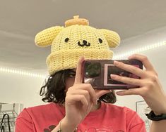 a woman taking a selfie with her cell phone wearing a crocheted hat