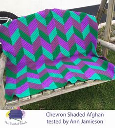 a purple and green blanket sitting on top of a wooden bench