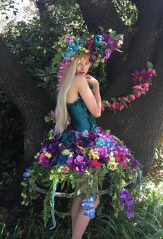 Recycled Renaissance, where Plain meets Haute Couture and the simplest dress is made Runway Ready!😊  This pictured Tropical Extravaganza began with a plain white one-size-fits-most hoop skirt which I started cutting apart to make shorter. . . added some green fabric spray paint. . . and let my imagination go to work! This whimsical skirt features dozens of different bright Tropical flowers and greenery to give it a jungle feel. The Tropical skirt is then paired with a purchased Teal corset and then decorated to coordinate with the Tropical theme. The elaborate headdress is the crowning glory! For custom orders please include your corset size in your order notes. The satin corset has a side zipper and Lace up ties in the back for tightening or loosening and is available in sizes: S: 28-30 Costume Fleur, Tropical Skirt, Floral Headdress, Recycled Dress, Flower Costume, Fair Outfits, Fest Outfits, Hoop Skirt, Fabric Spray