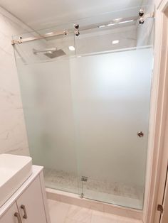 a white bathroom with a glass shower door