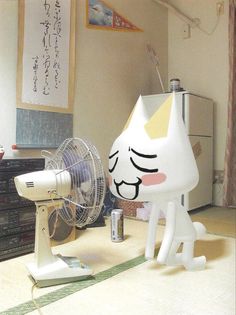 a white cat sitting on top of a table next to a fan