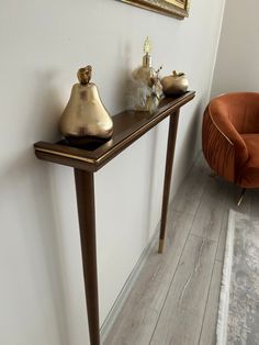 a table with two vases on it next to a chair and a painting hanging on the wall