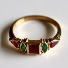 A garnet center is flanked by contrasting emerald and delicate blossoms of rubies. Unforgettable charm. Emerald And Garnet Ring, Ruby Emerald Ring, Multi-stone Emerald Ring As A Gift, Emerald Multi-stone Birthstone Ring Gift, 14k Gold Multi-stone Emerald Ring Gift, 14k Gold Multi-stone Emerald Ring As A Gift, Multi-stone 14k Gold Ruby Ring For Gift, Emerald Cut Multi-stone Ruby Jewelry, Elegant Red Multi-stone Birthstone Ring