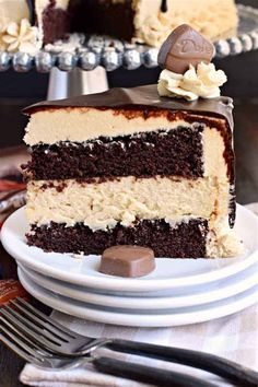 a slice of chocolate cake with white frosting on a plate next to a fork