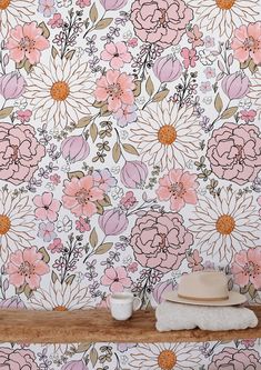 a floral wallpaper with pink and white flowers on it, next to two cups