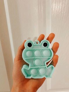 a hand holding a frog shaped container with holes in it's body and eyes