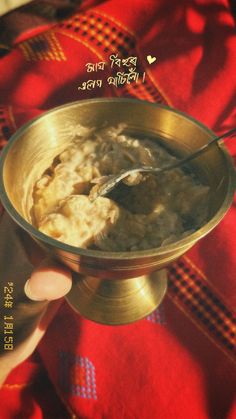 a person is holding a metal bowl with food in it on a red table cloth