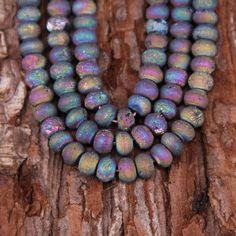 three strands of multicolored glass beads sitting on top of a piece of wood