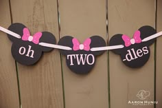 two minnie mouse ears with pink bows are hanging on a fence, which says oh two sides