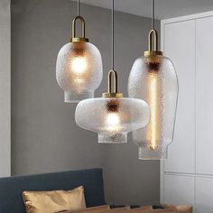 three glass lights hanging from the ceiling in a room with a couch and table next to it