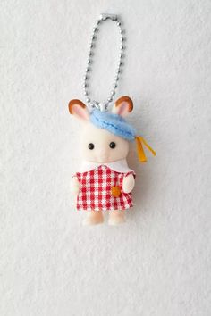 a keychain with a small animal wearing a red and white checkered dress