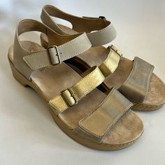 Excellent Preowned Condition. No Signs Of Wear Possibly Never Worn. Easy Velcro Closure On All 3 Straps. Metallic And Taupe Color. Size 40. Leather Closed Toe Wedge Sandals With Adjustable Strap, Gold Leather Double Strap Sandals, Gold Leather Wedge Sandals With Cushioned Footbed, Gold Double Strap Leather Sandals, Gold Leather Round Toe Wedge Sandals, Gold Leather Wedge Sandals With Round Toe, Casual Gold Leather Wedge Sandals, Gold Open Toe Leather Wedge Sandals, Gold Leather Footbed Sandals With Buckle Closure