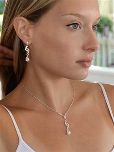 a woman wearing a necklace and earring with pearls on it's sides, looking off to the side