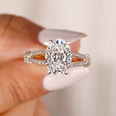 a woman's hand holding a ring with a large diamond in the center and two rows of diamonds on each band