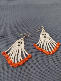 two pairs of beaded earrings with orange and white beads hanging from them on a gray surface