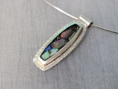 "sterling silver inlaid with Weló opal composite.  18\" sterling silver neck wire with a tension clasp 30mm x 11mm x 4mm" Modern Oblong Jewelry With Polished Finish, Iridescent Oval Sterling Silver Jewelry, Unique Opal Necklaces For Formal Occasions, Elegant Opal Necklace With Large Pendant, Elegant Silver Opal Jewelry, Nickel-free Oblong Sterling Silver Jewelry, Modern Inlay Jewelry As A Gift, Modern Formal Opal Jewelry, Modern Handmade Oblong Jewelry