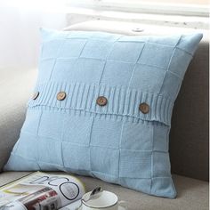 a blue pillow sitting on top of a couch next to a cup and saucer