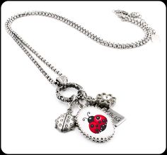 a ladybug necklace is hanging from a chain on a white background with the word love written below it