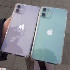 two iphones that are sitting next to each other on a street side with people holding their cell phones