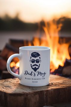 a white coffee mug sitting on top of a wooden table next to a fire pit