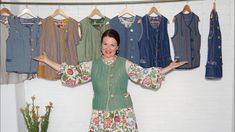 a woman standing in front of a rack of clothes with her hands out to the side