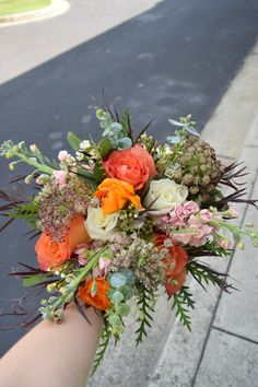 a bouquet of flowers is being held on the arm of a person's hand