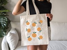 a woman holding a bag with oranges on it