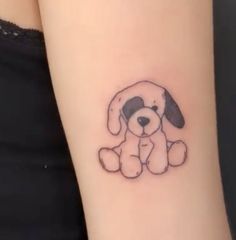 a small dog tattoo on the arm with a black and white puppy sitting next to it