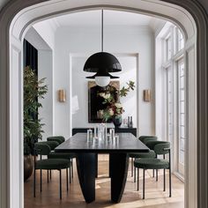 the dining room table is surrounded by green chairs and an oval black chandelier