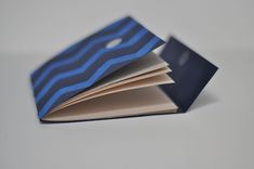 an open book with blue and black stripes on the pages, sitting on a white surface