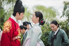 two people dressed in traditional chinese clothing standing next to each other with trees in the background