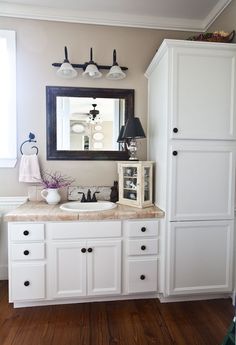 a bathroom with white cabinets and a mirror