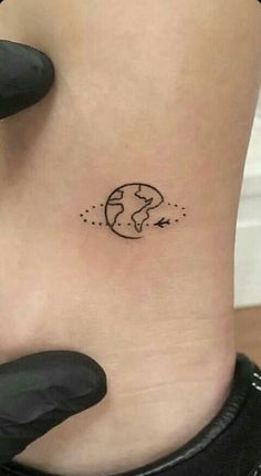 a small earth tattoo on the side of a woman's ribcage is shown