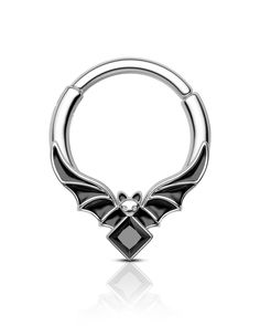 a black and white photo of an open ring with wings on the front, and a diamond in the middle