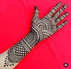 the hand is decorated with black and white henna designs on red background, closeup