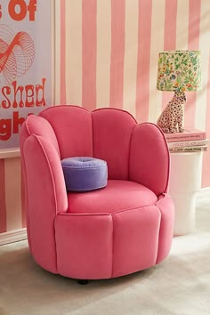 a pink chair with a purple pillow on it in front of a striped wallpaper