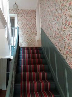 the stairs are lined with floral wallpaper and striped rugs, along with matching handrails